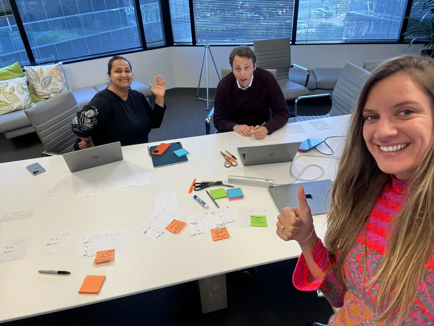 Sara and colleagues smiling around a table after a brainstorming session