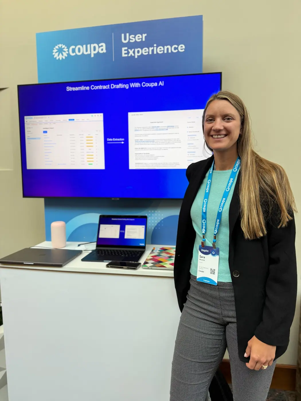 Sara smiling at Coupa Inspire beside a User Experience demonstration